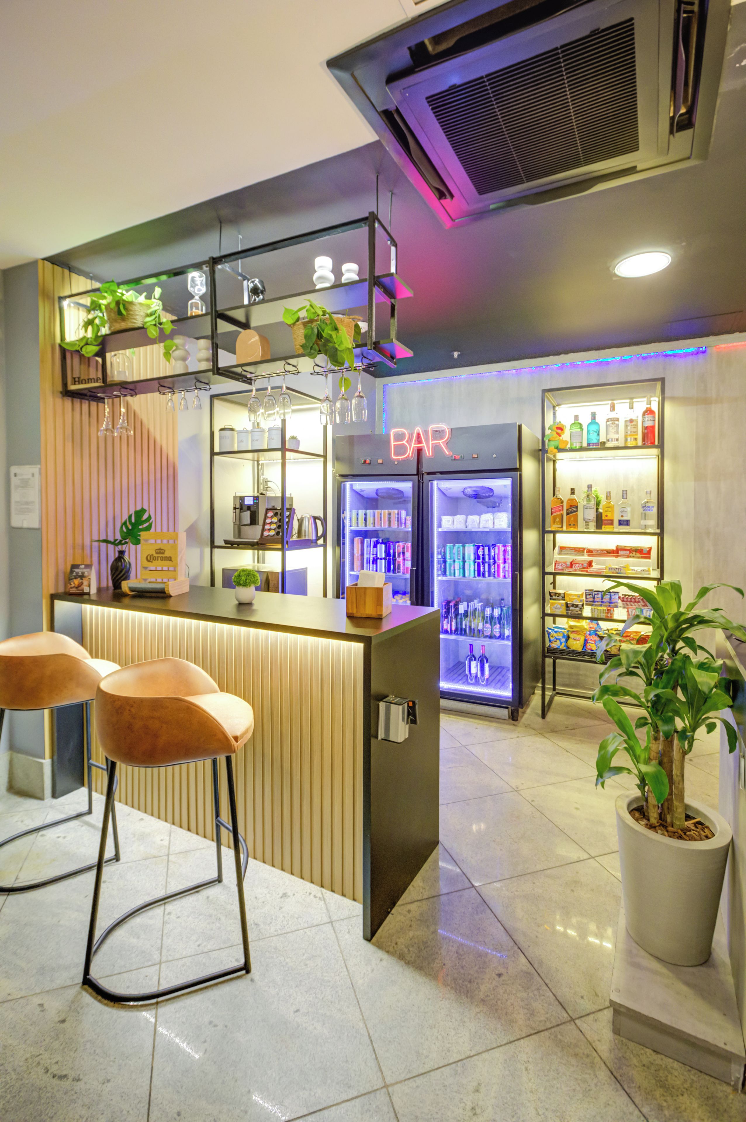 Un espace bar comprenant un comptoir, des tabourets et un réfrigérateur rempli de boissons.