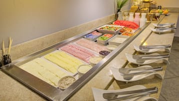 A buffet with various food options and utensils laid out on a counter.