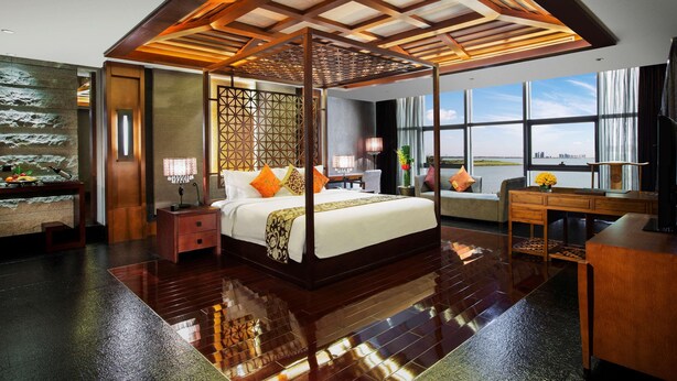 A spacious bedroom with a large bed, a desk, and a view of the city.