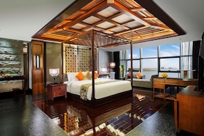 A spacious bedroom with a large bed, a desk, and a view of the city.