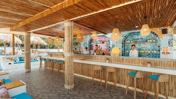 A bar area with a wooden ceiling, bamboo columns, and colorful tiled walls.