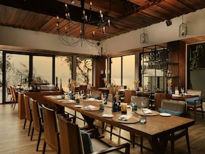 A dining area with a long wooden table, chairs, and a chandelier. - Pullman Phuket Arcadia Naithon Beach (Sa Khu)