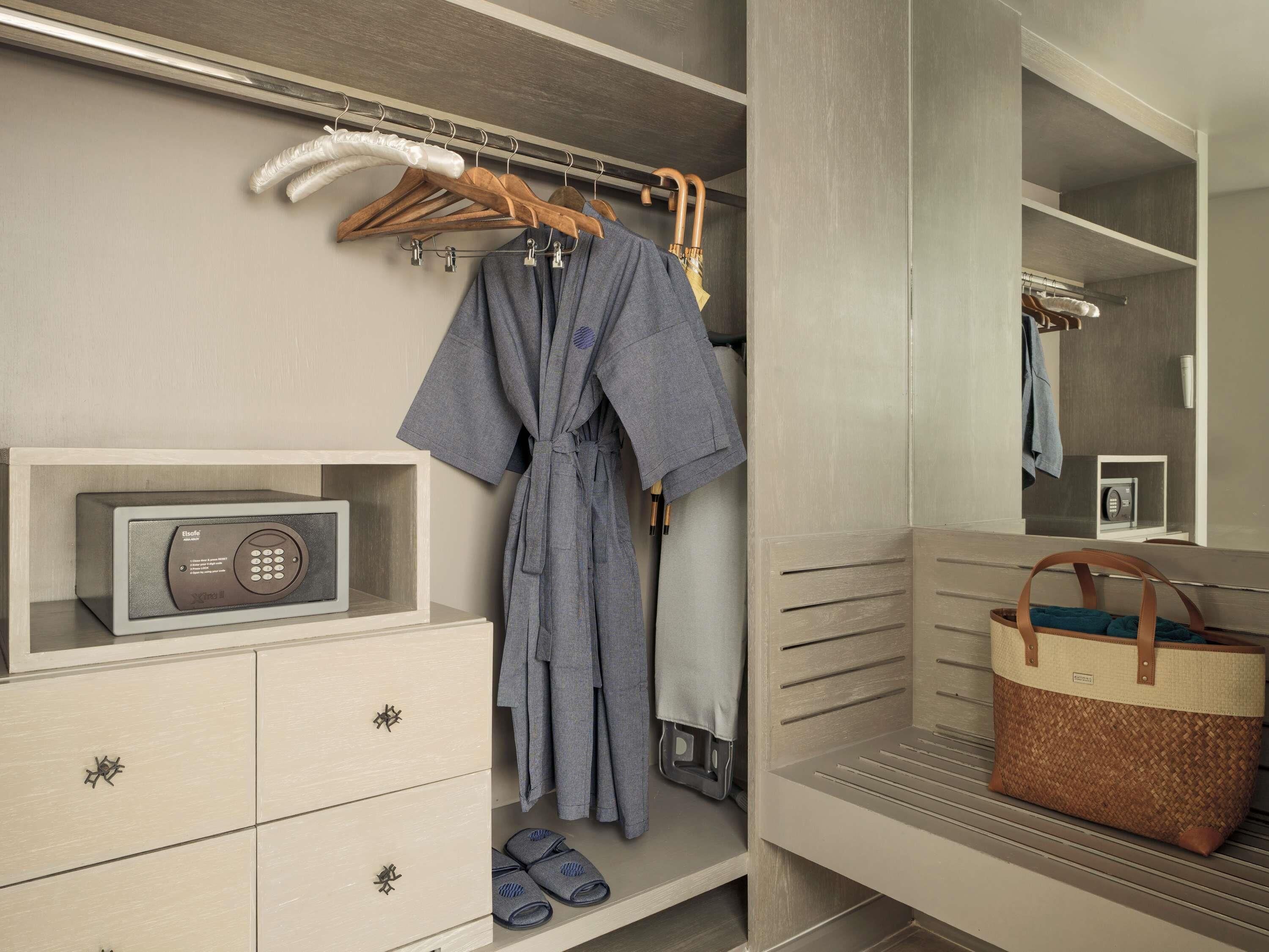 A walk-in closet with a robe hanging, a radio, a basket, and a mirror.