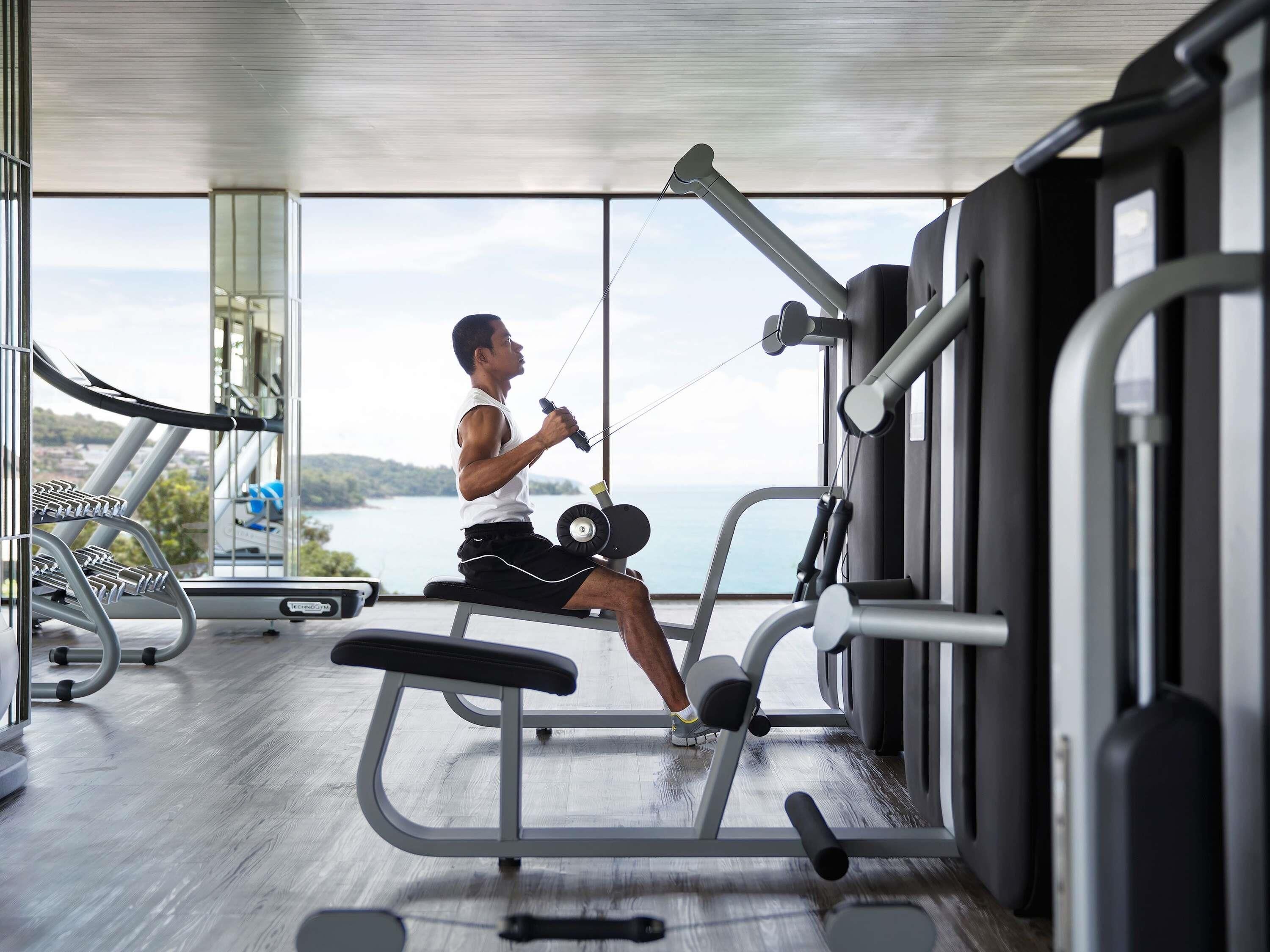 A gym with exercise equipment, large windows, and a view of the outdoors.