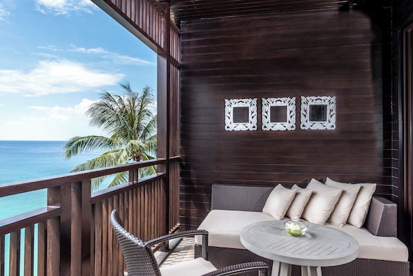A balcony with a view of the ocean, a wicker sofa with cushions, and a small round table with a glass vase. - Pullman Phuket Arcadia Naithon Beach (Sa Khu)