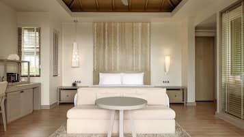 A bedroom with a bed, bedside tables, a round table, a ceiling fan, and a large window with blinds.