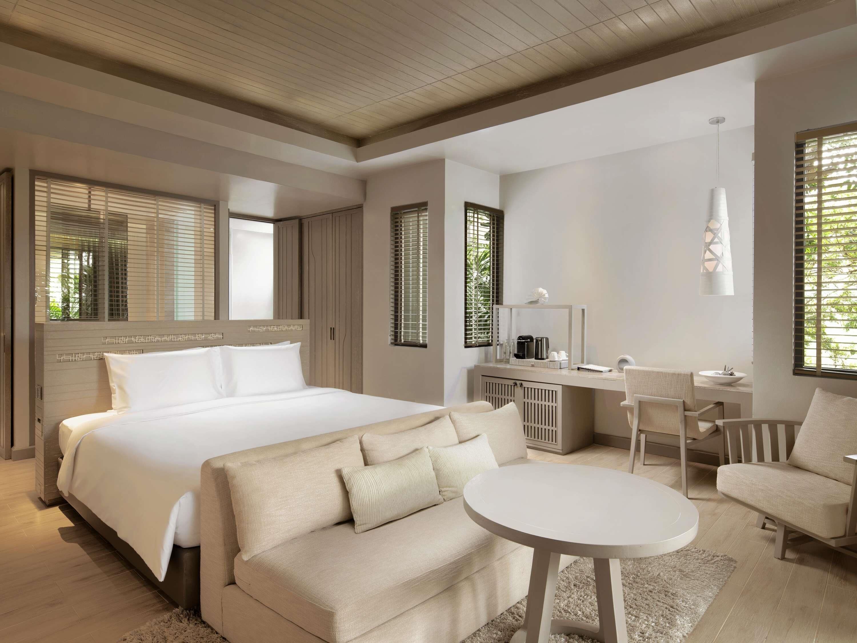 A modern bedroom with a large bed, a sofa, a desk, and a chair.