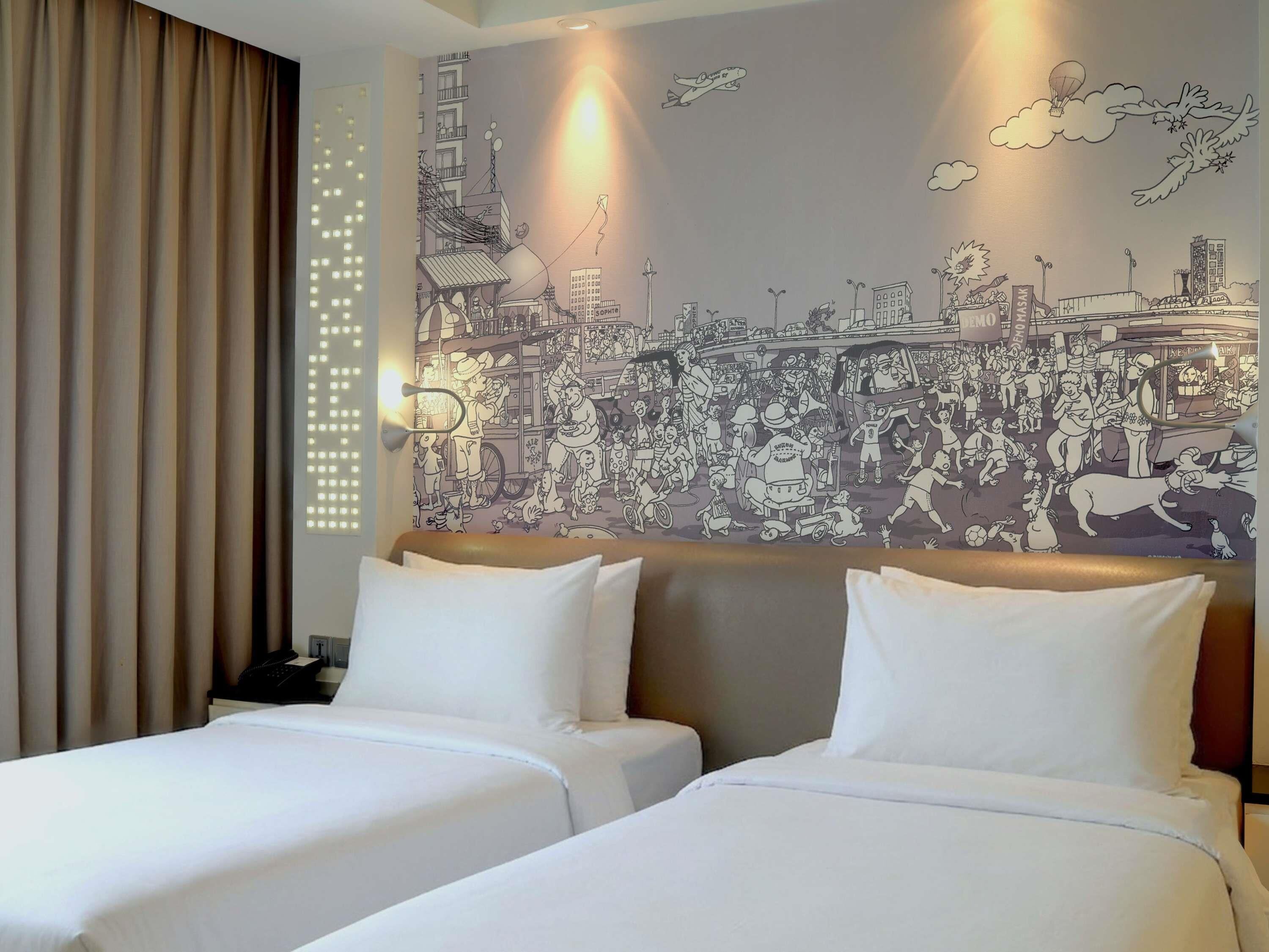 Habitación de hotel con dos camas, un mural de paisaje urbano en la pared y una ventana con cortinas.
