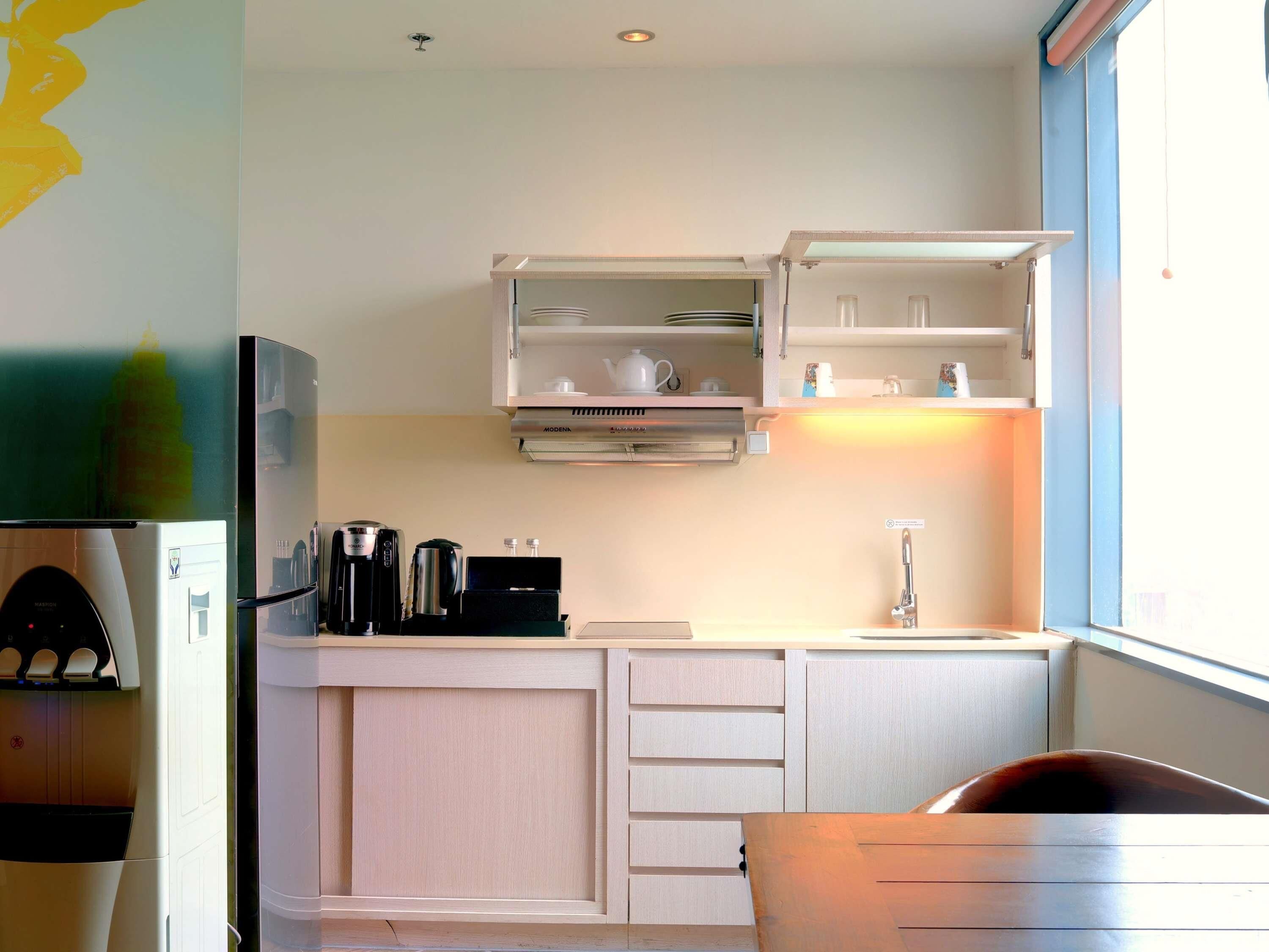 A compact kitchen with a built-in coffee maker, a microwave, and a sink.