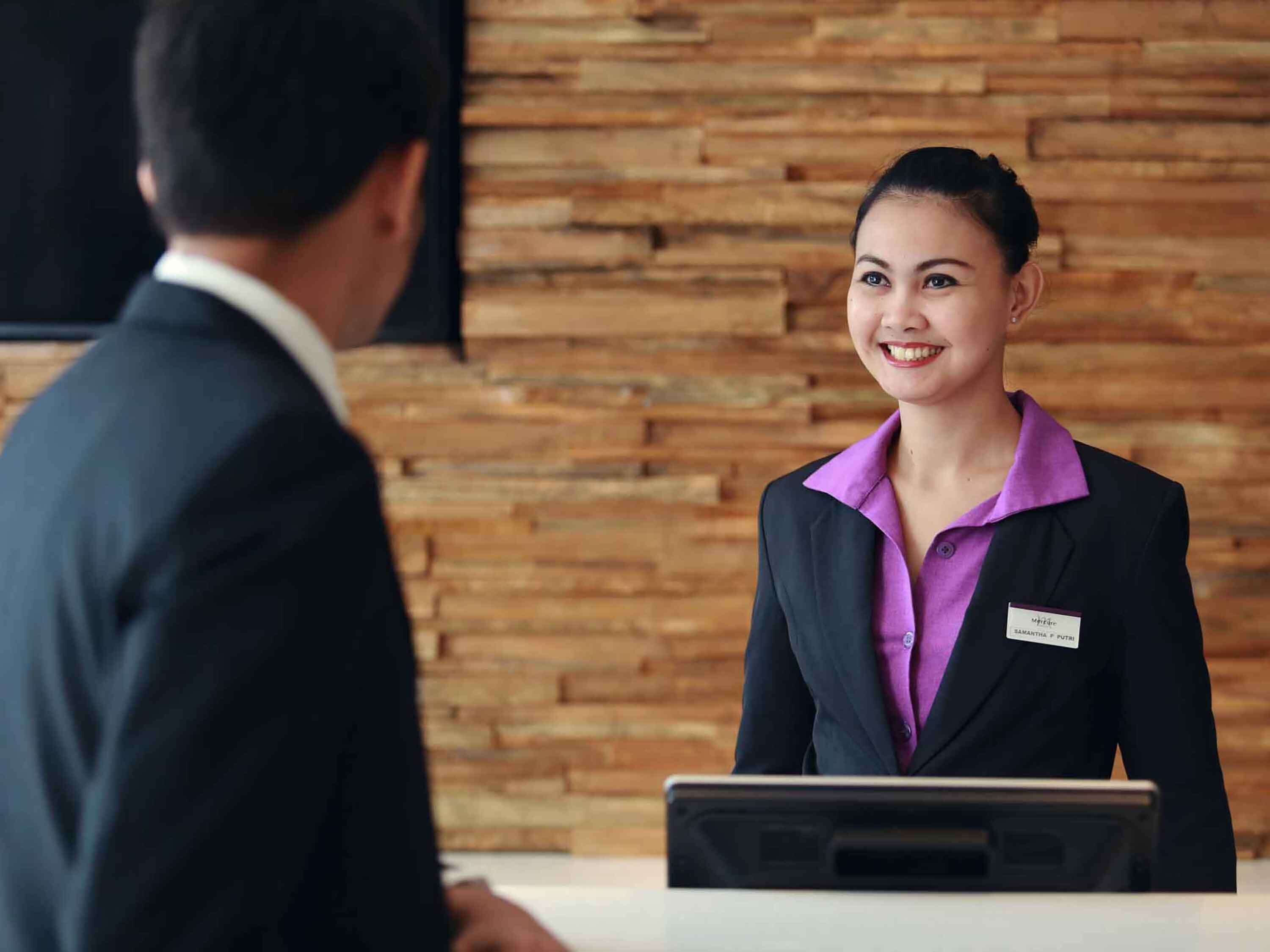 A hotel reception area with a wooden wall background and a reception desk.