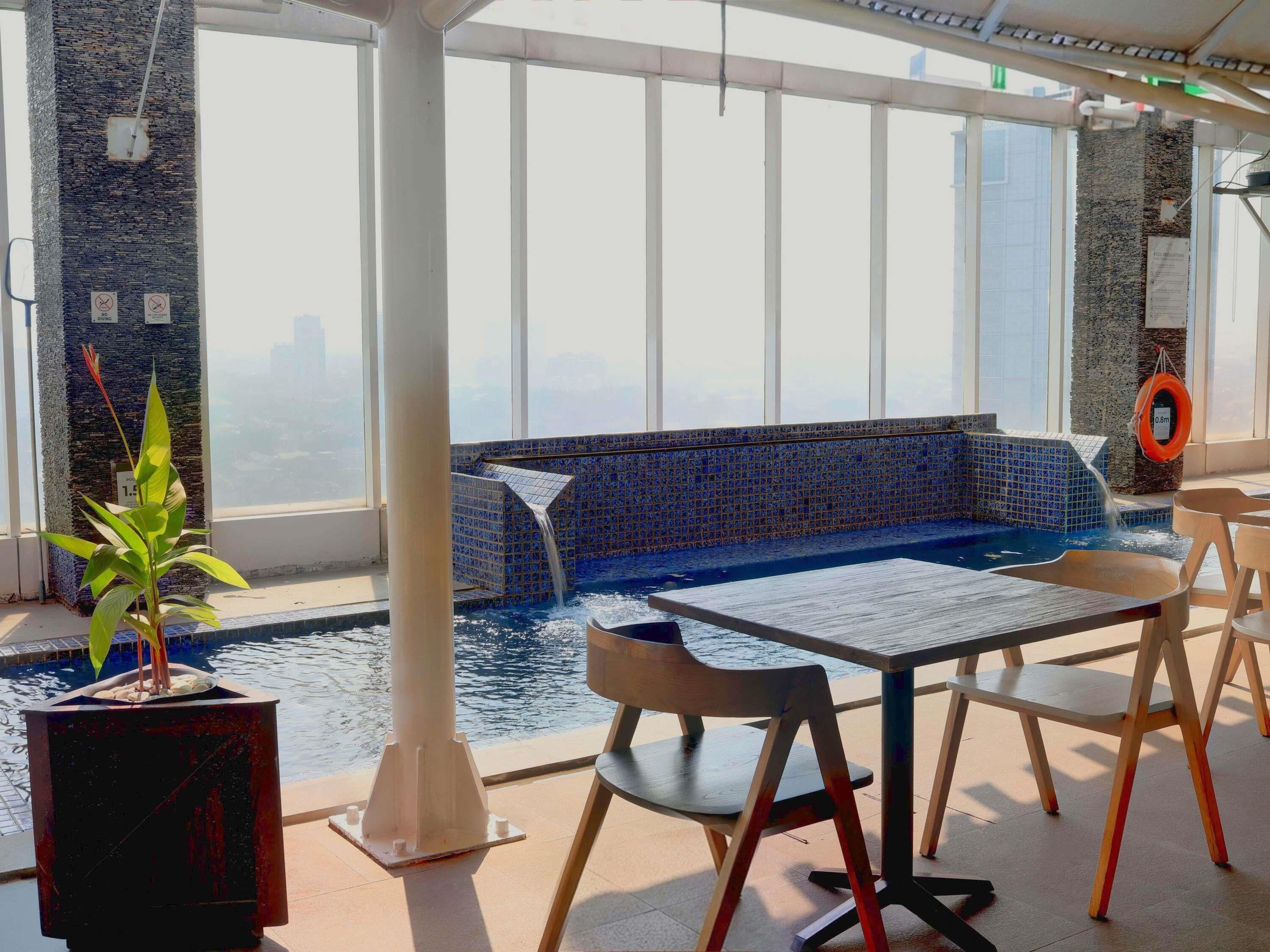 Area piscina con parete in mosaico blu, zona relax e pianta in vaso.