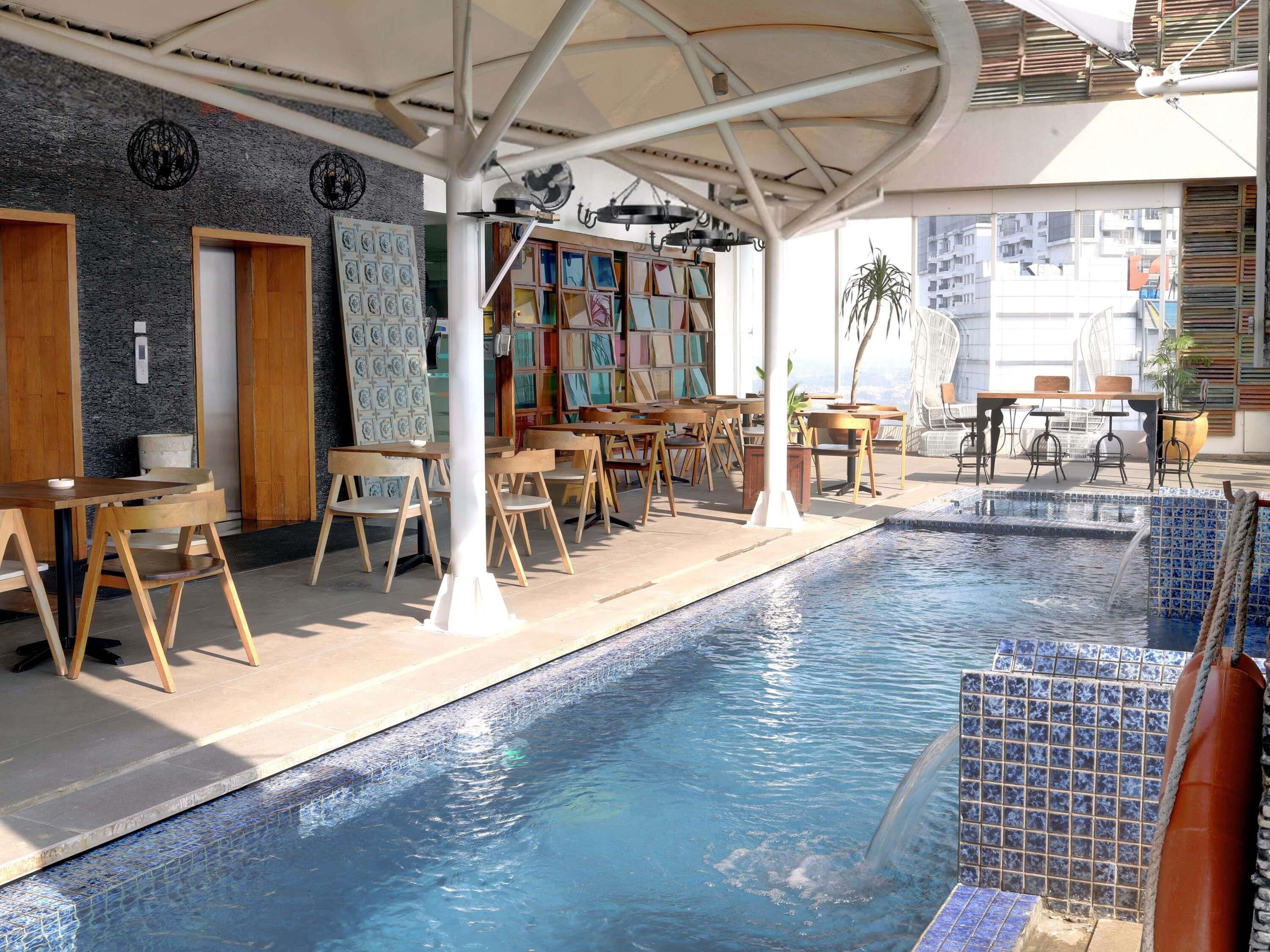 Una piscina interior con paredes de azulejos, muebles de madera y estructura en el techo.