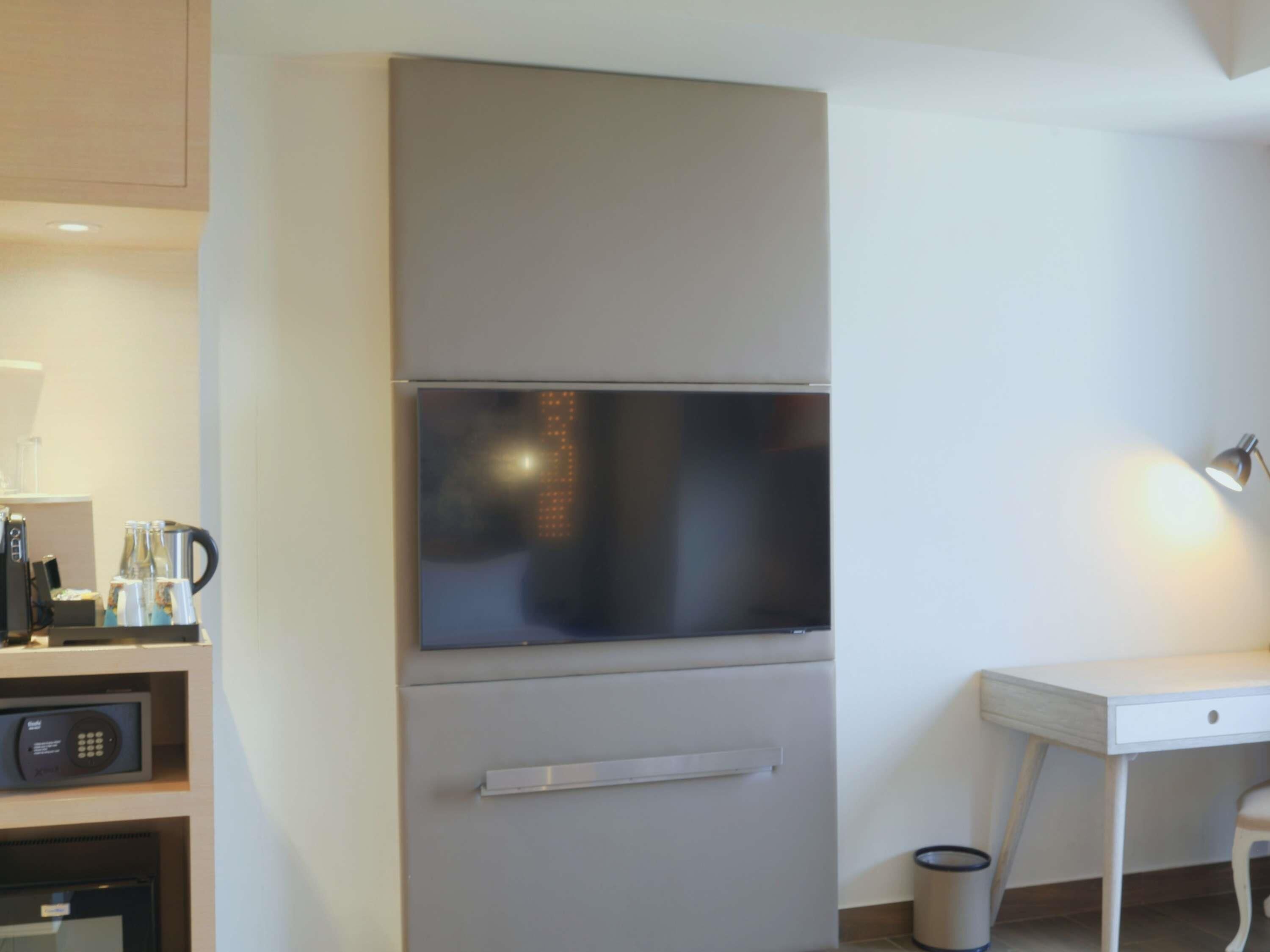 Una kitchenette con microondas, cafetera y armarios para almacenamiento.