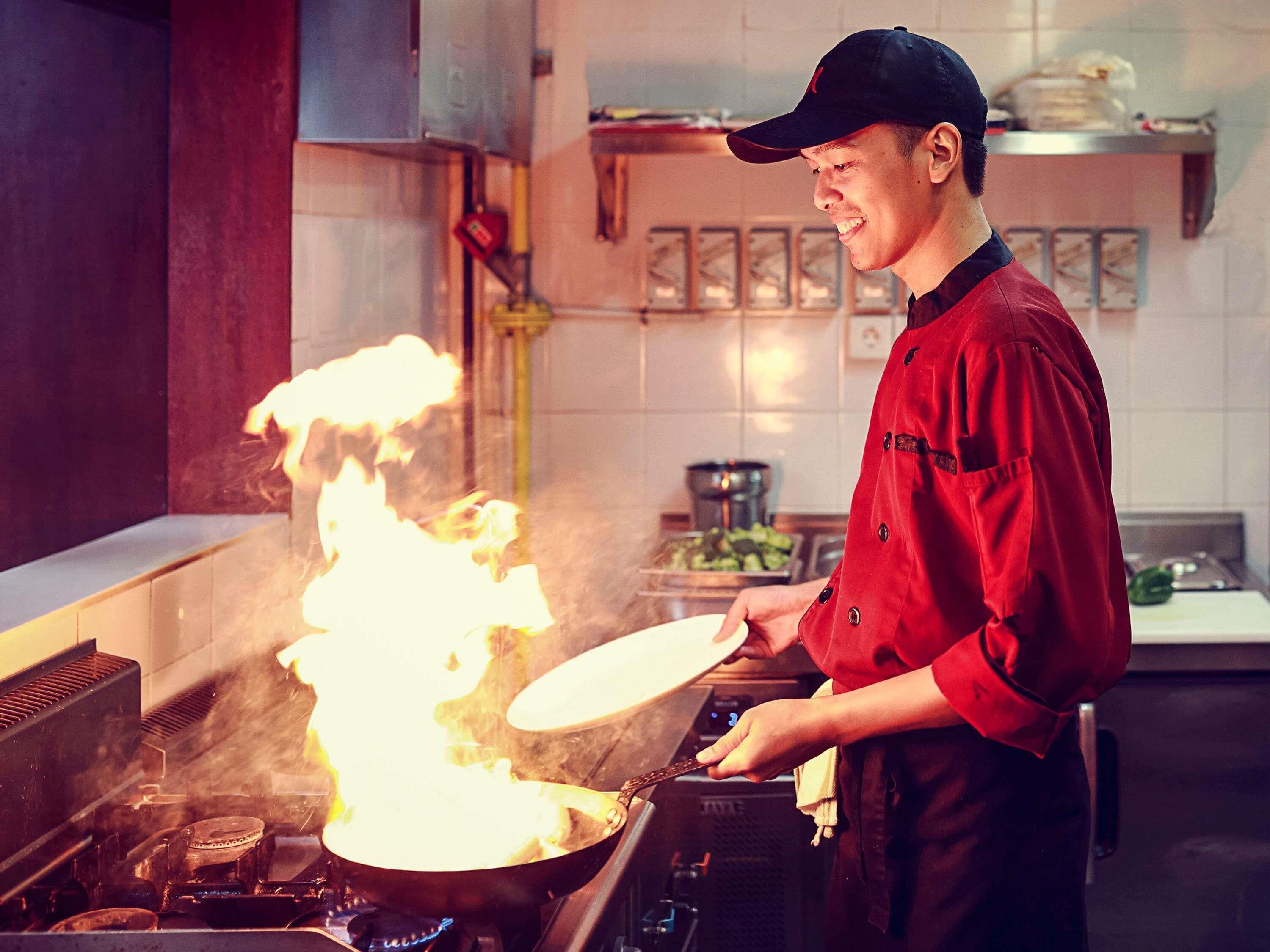 Un chef cocina con llamas en una cocina.