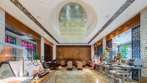 A spacious lobby with a central seating area, a large chandelier, and a reception desk with a menu display. - Holiday Inn Resort Chaohu Hot Spring by IHG (Hefei)