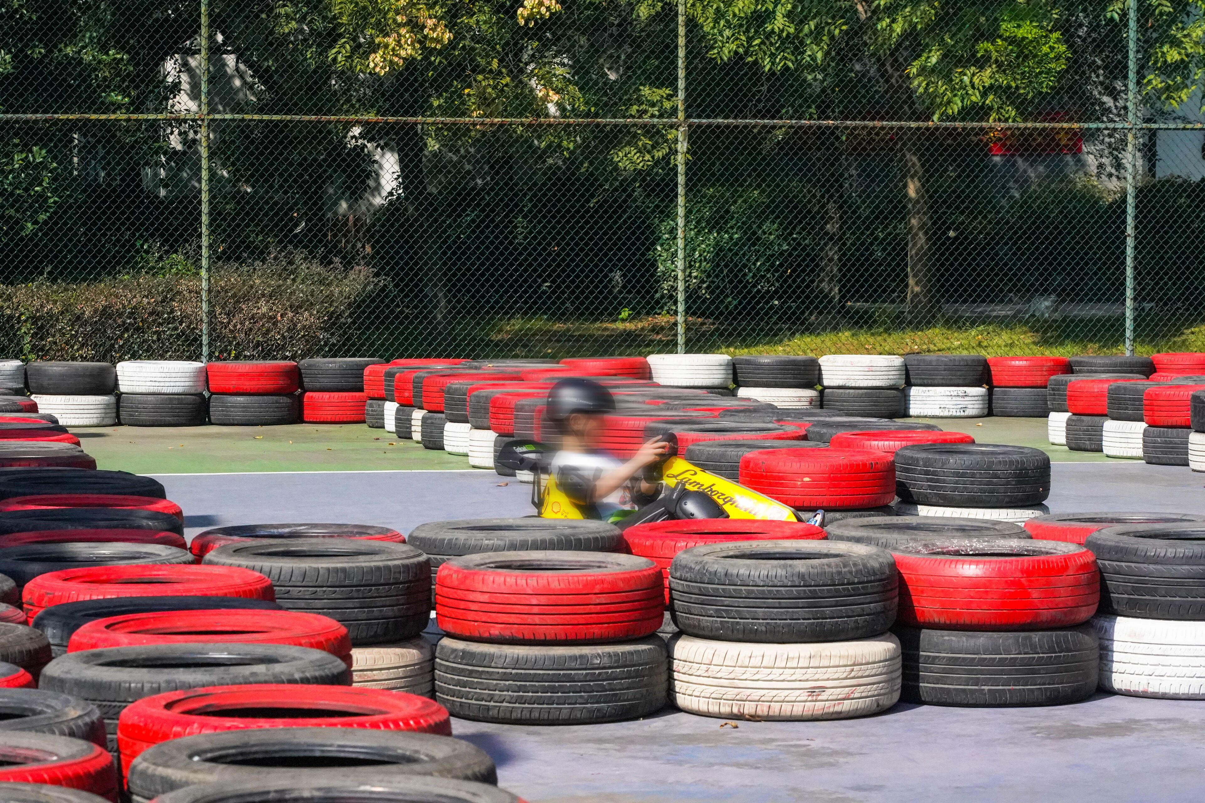 Una pista de karts con varias filas de neumáticos y una persona con una camiseta amarilla.