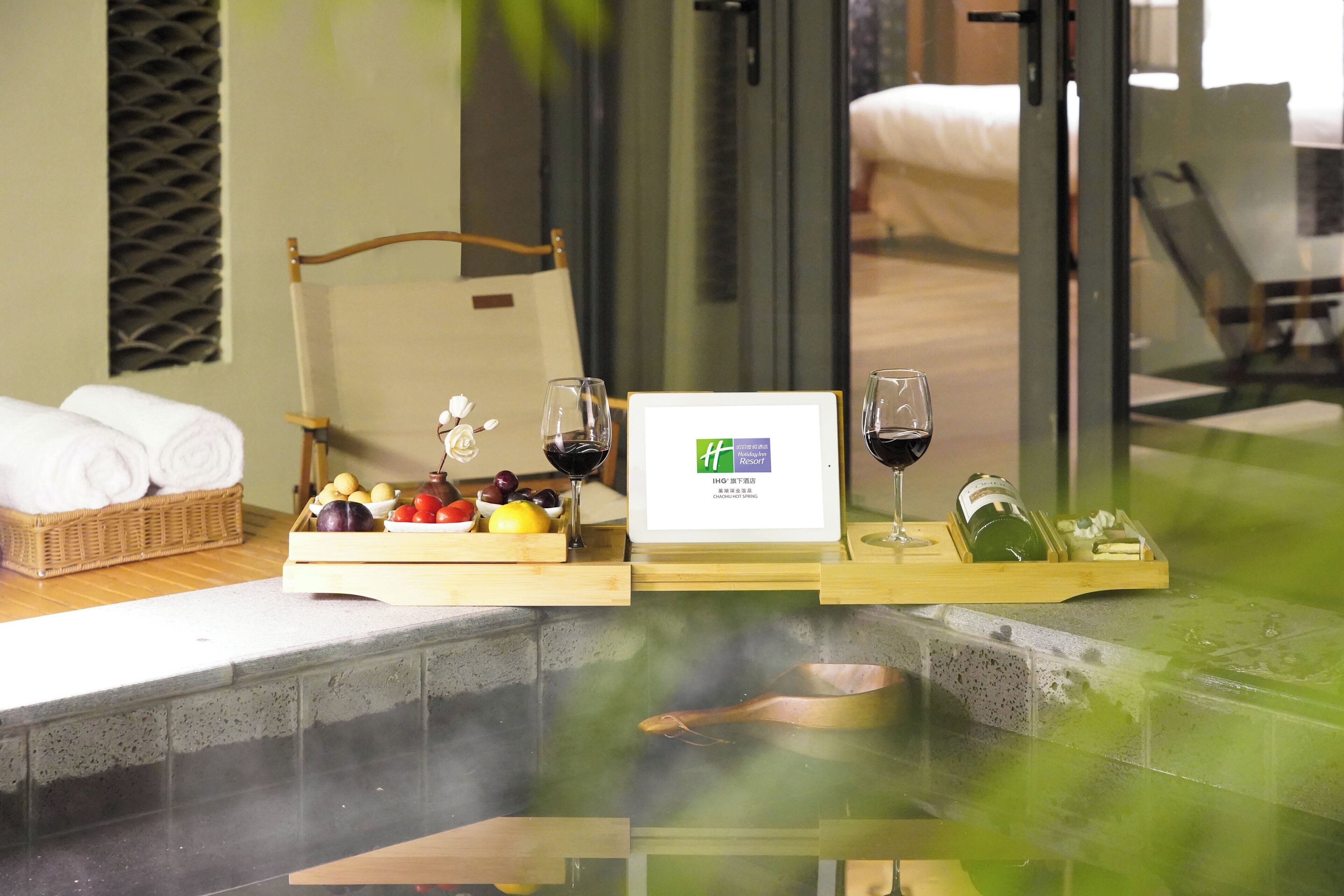 A spa area with a hot tub, wooden trays with fruits, wine glasses, and a framed sign.