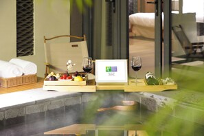 A spa area with a hot tub, wooden trays with fruits, wine glasses, and a framed sign. - Holiday Inn Resort Chaohu Hot Spring by IHG (Hefei)