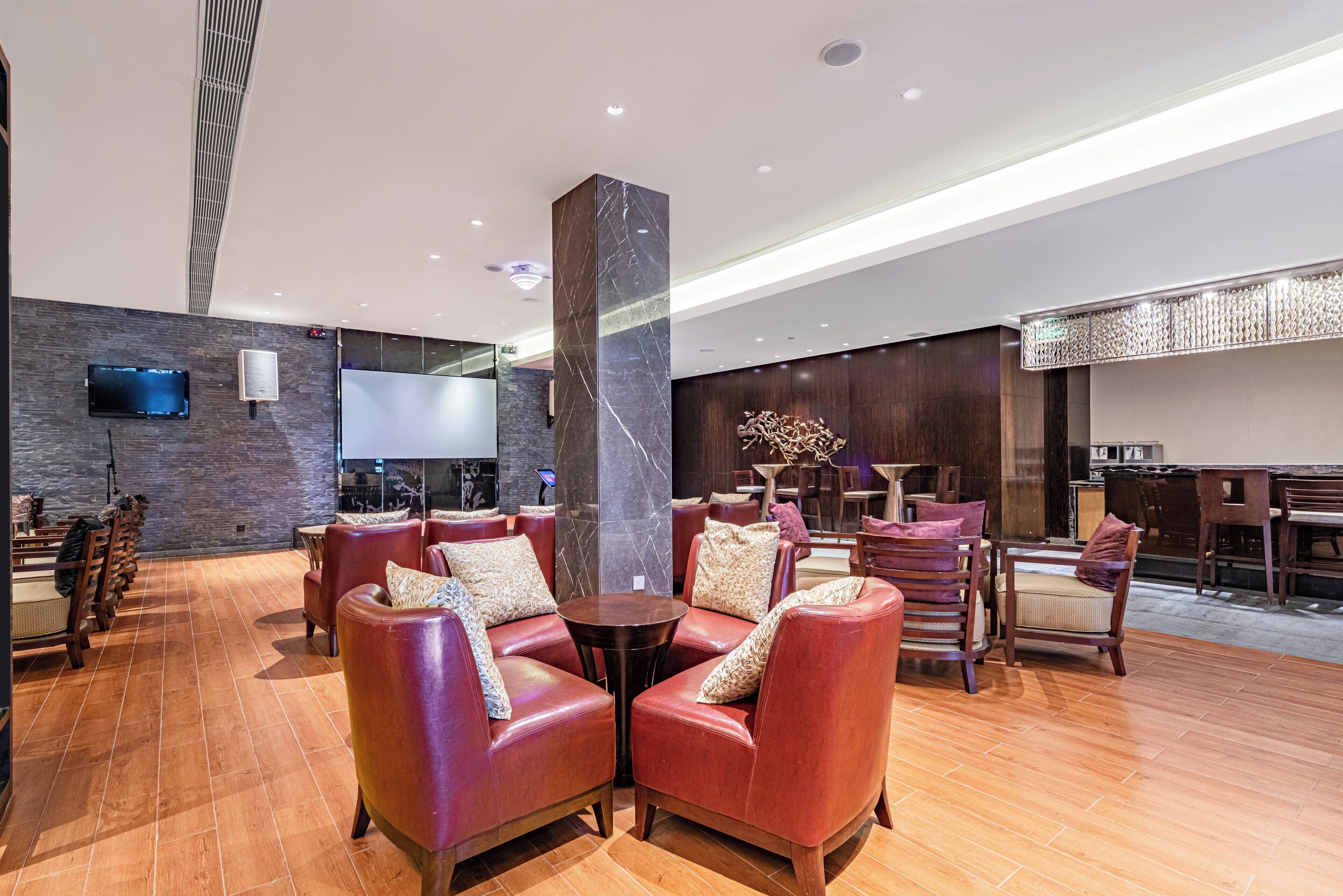Eine moderne Lobby mit Ledersitzgelegenheiten, einer großen Säule und einem Flachbildfernseher an der Wand.
