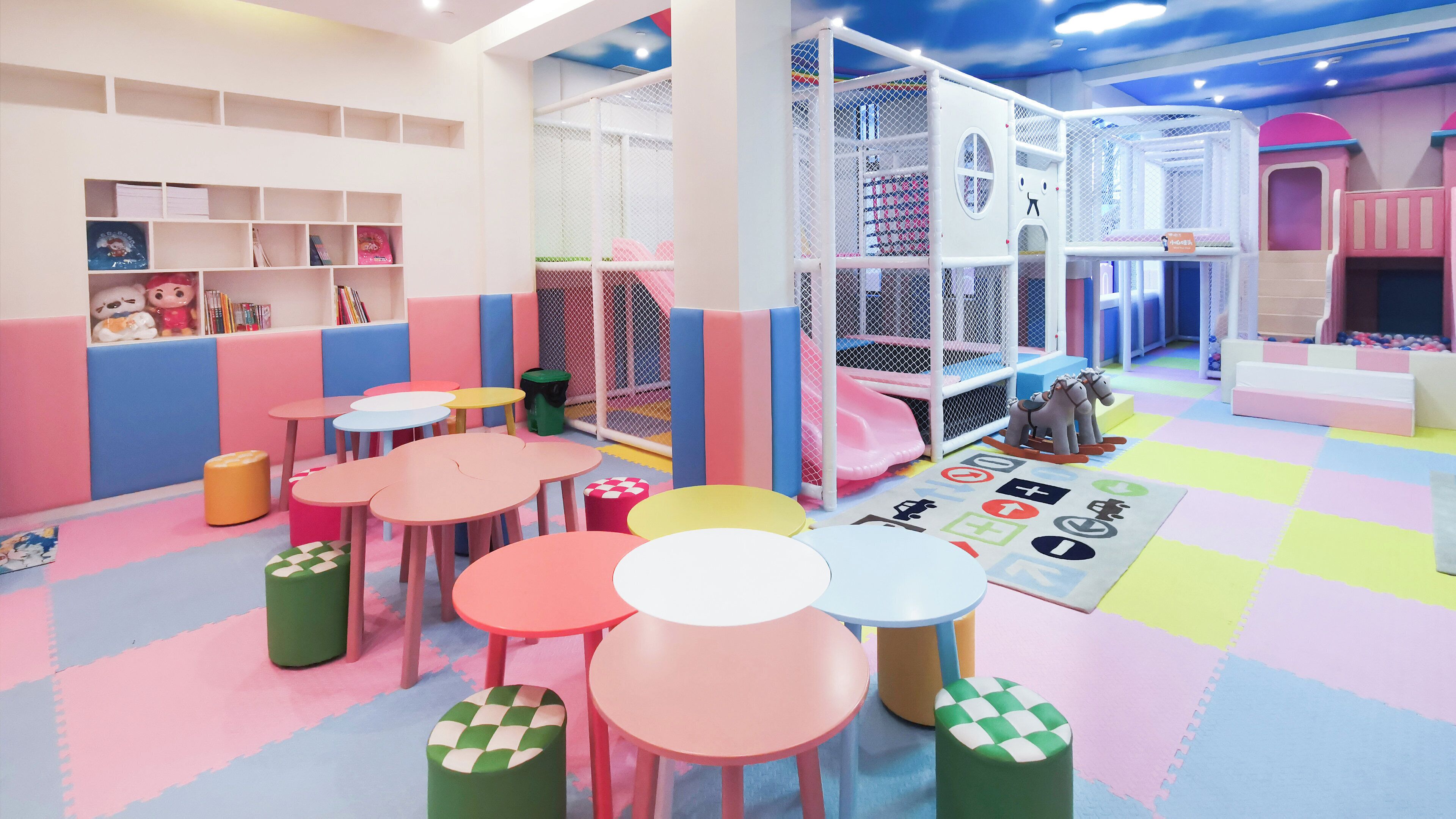 A children's play area with colorful tables, chairs, and a soft play zone.