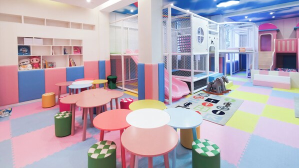 A children's play area with colorful tables, chairs, and a soft play zone.