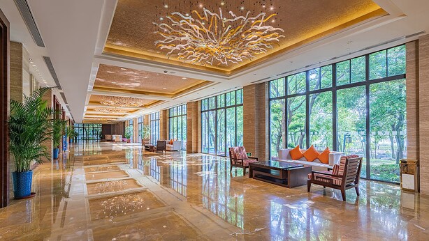 A spacious lobby with a polished marble floor, large windows offering a view of greenery, and a modern chandelier. - Holiday Inn Resort Chaohu Hot Spring by IHG (Hefei)