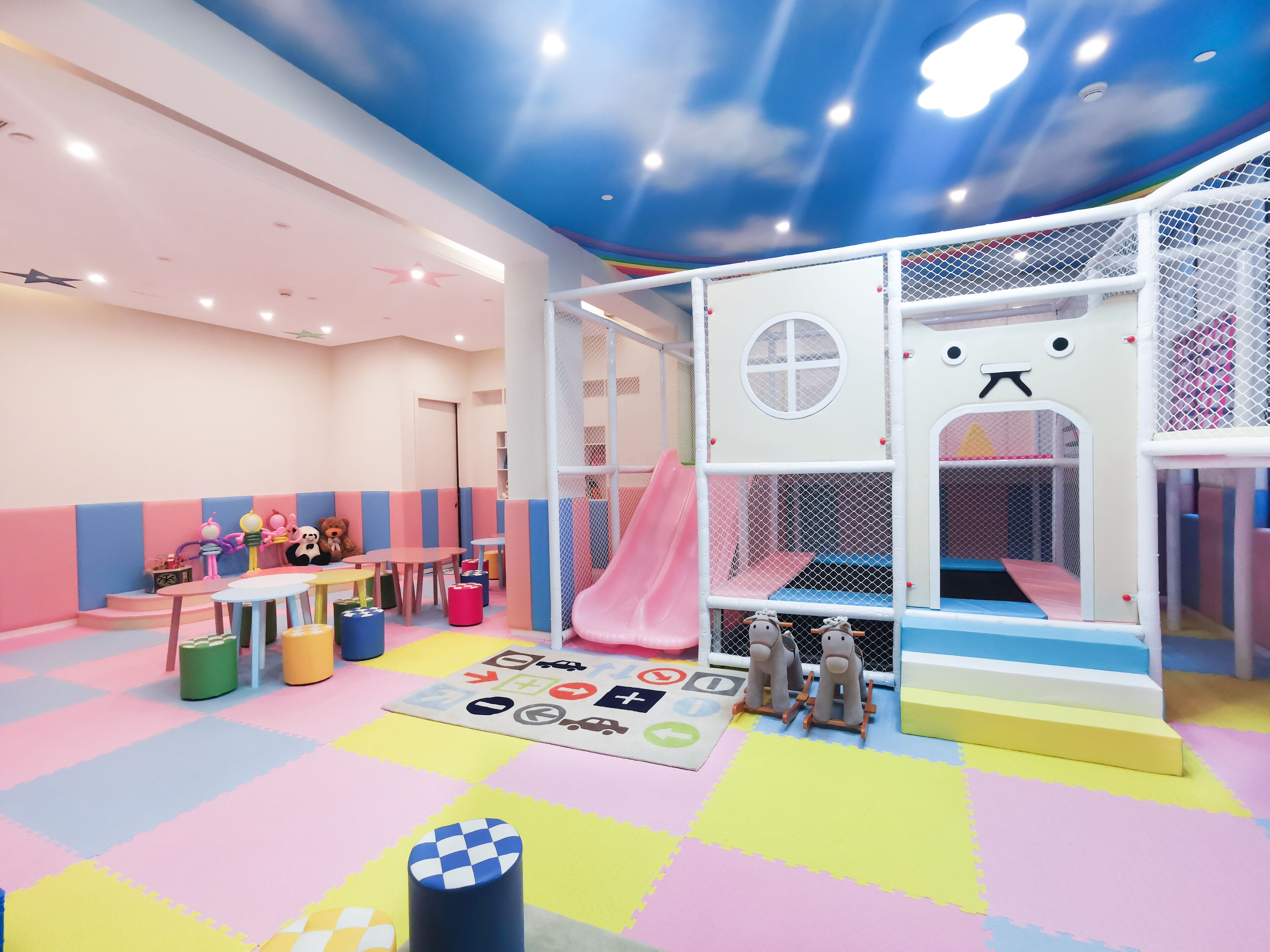 Zona infantil con tobogán, parque infantil y suelo de colores.