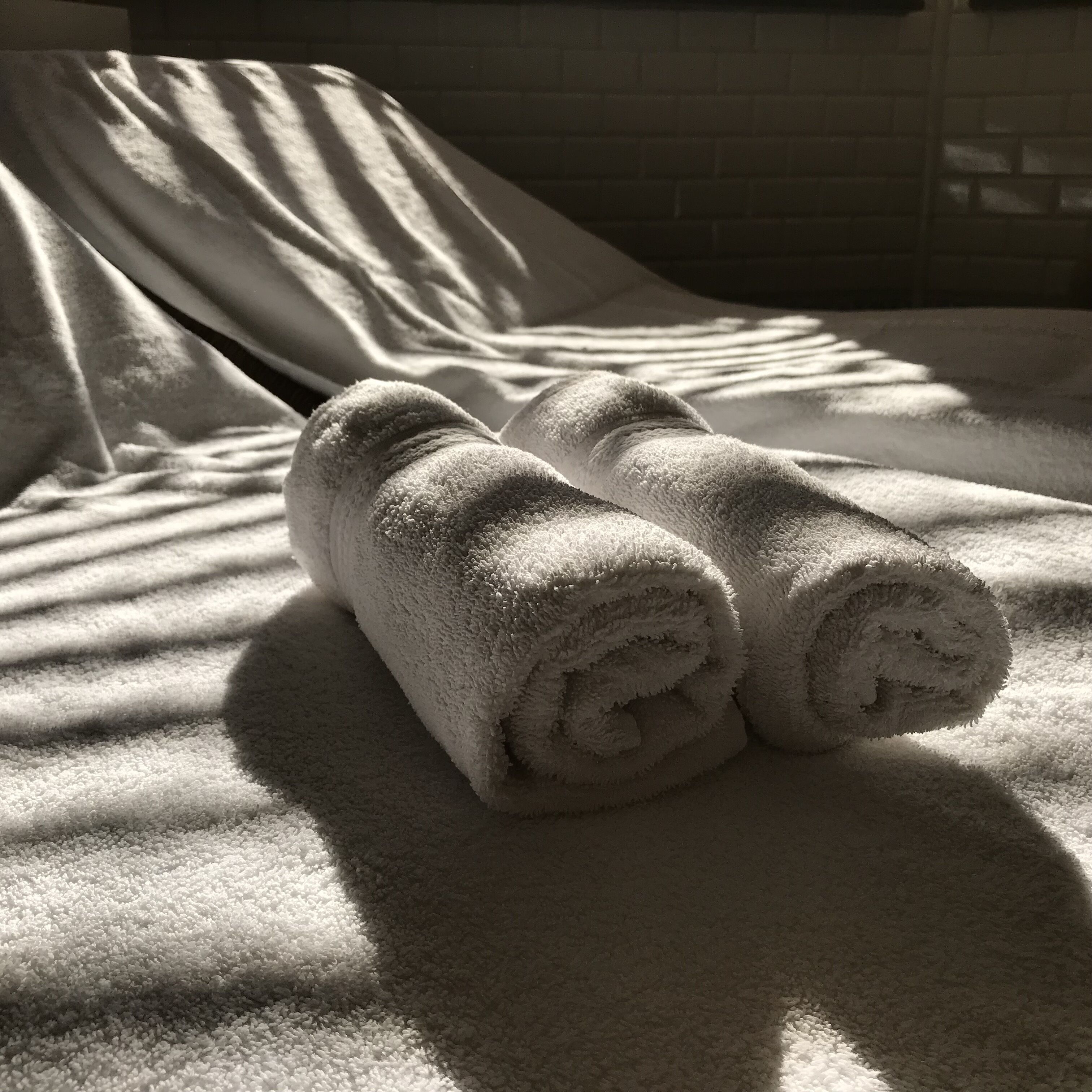 A bed with rolled white towels and a white blanket.