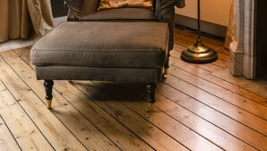 Una habitación con un sillón oscuro, una lámpara de pie y una chimenea.