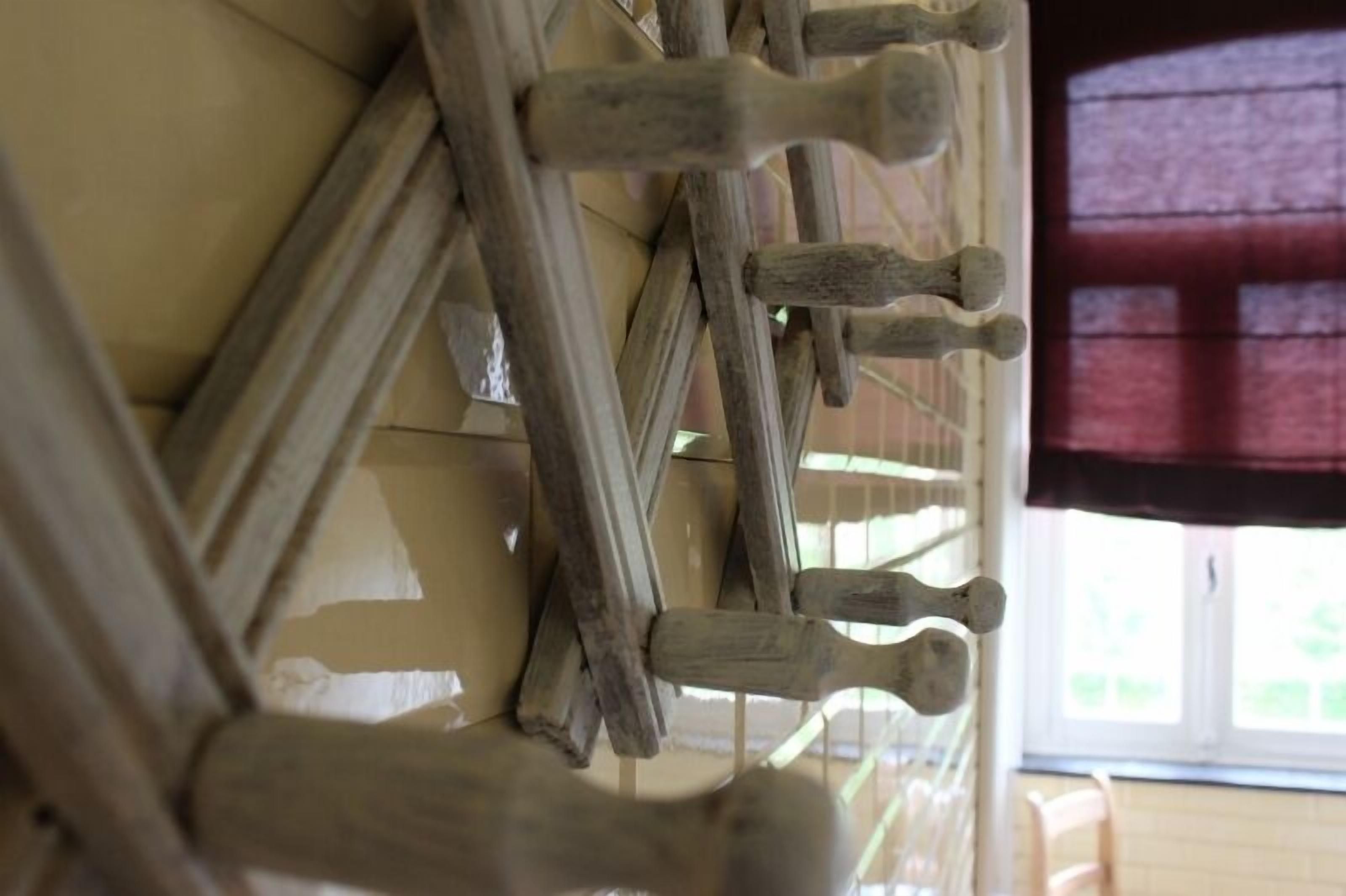 A wooden rack with multiple hooks against a wall, likely for hanging items.