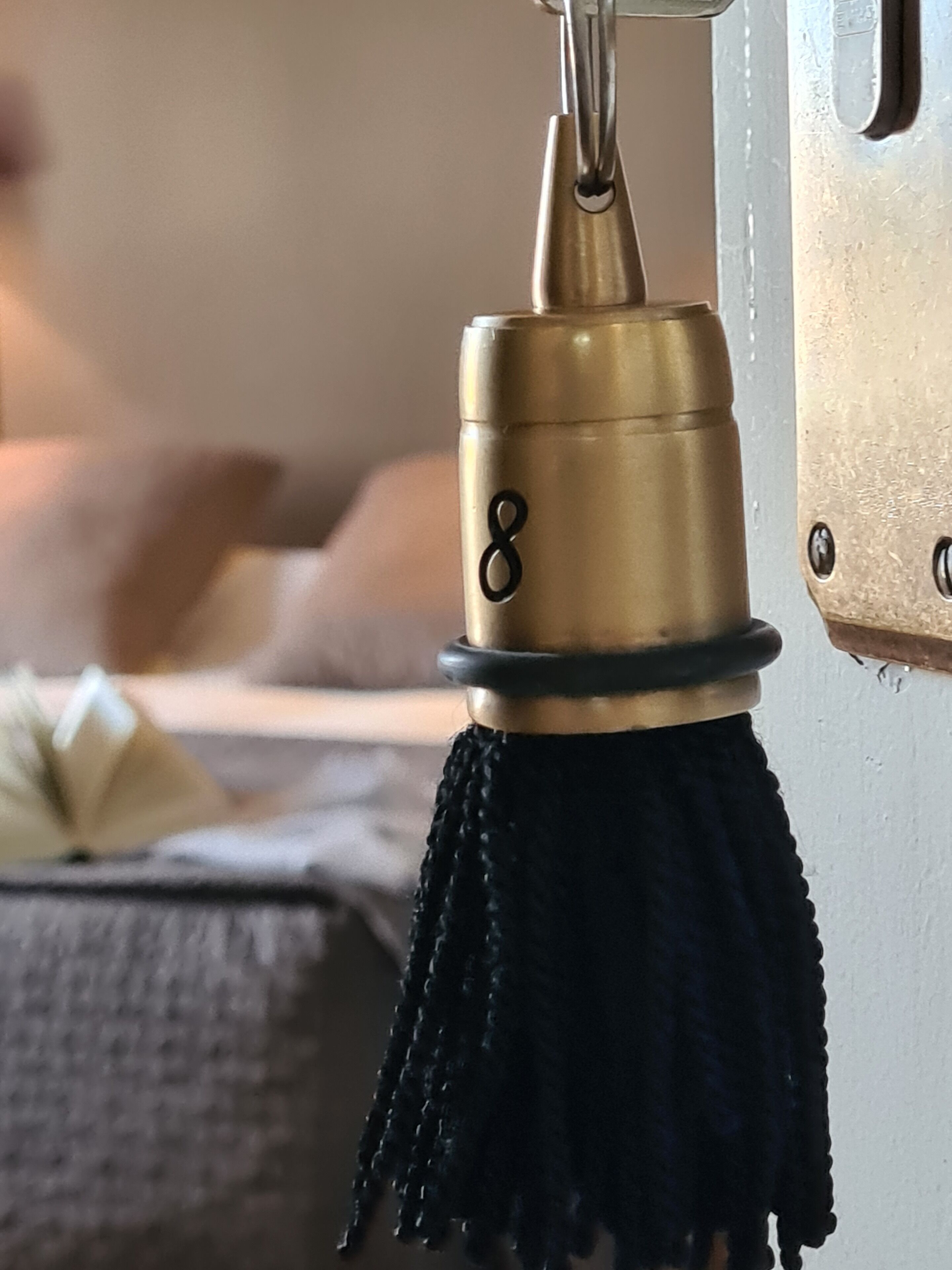 A brass door handle with a black tassel and the number 8.