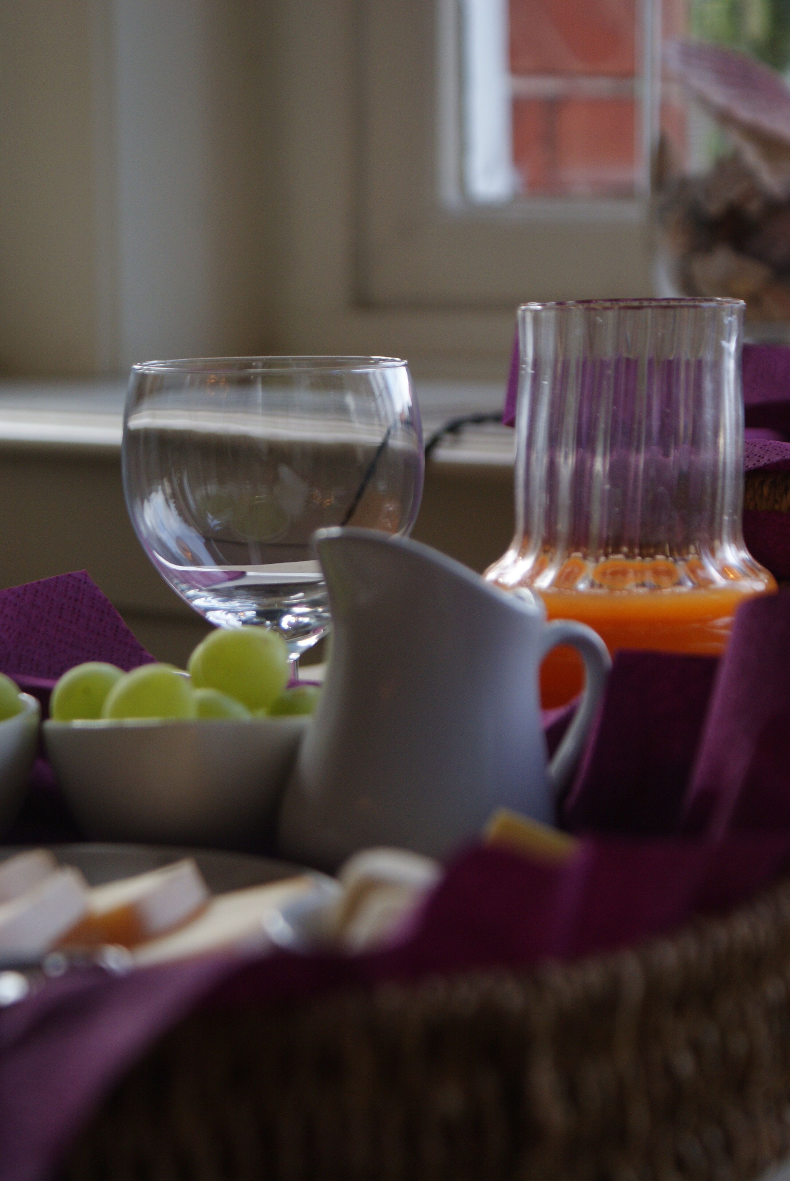 A table with a pitcher, a glass, and a bowl of fruit.