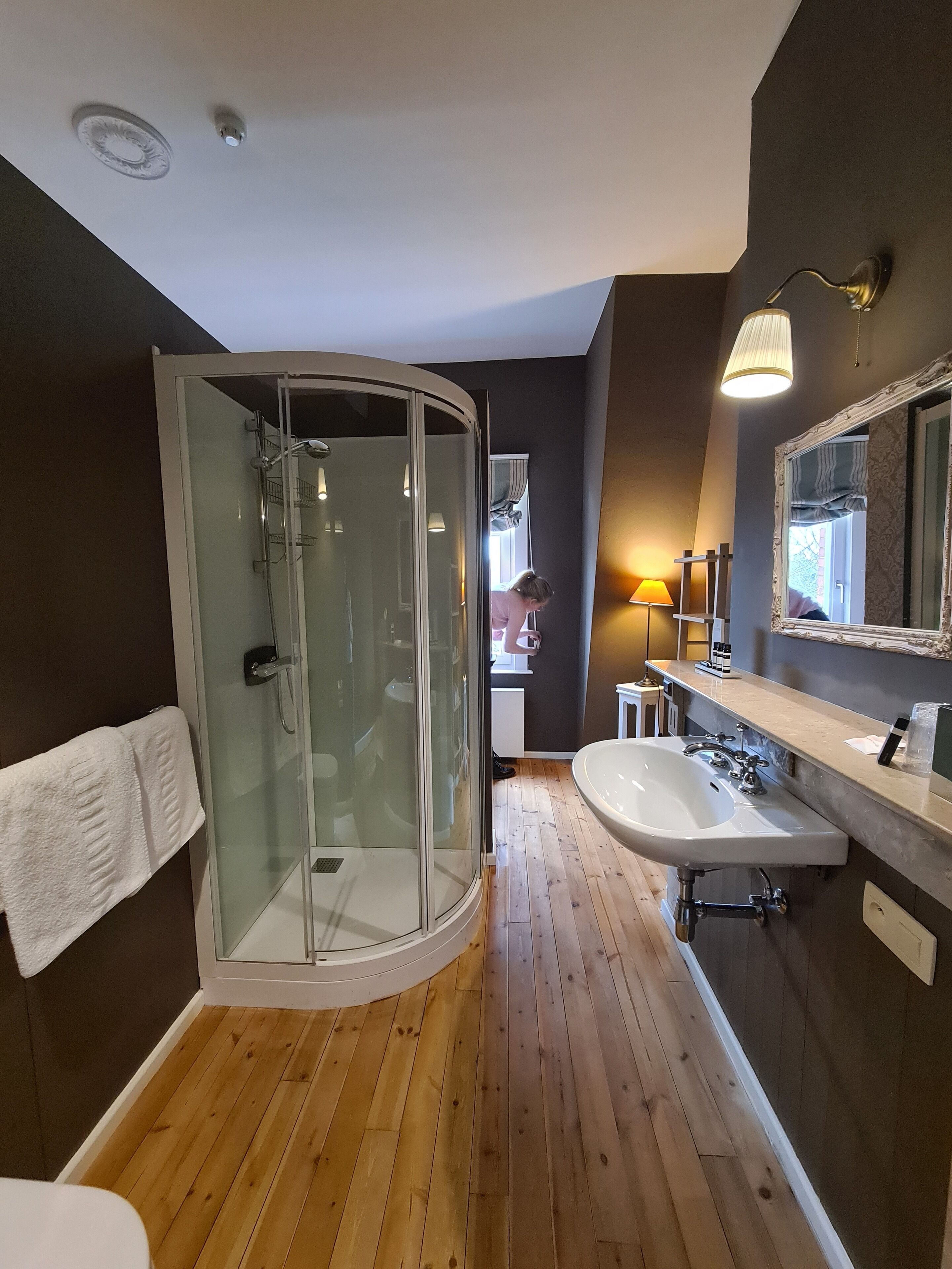 A modern bathroom with a glass-enclosed shower, a white sink, and a vanity with a mirror.
