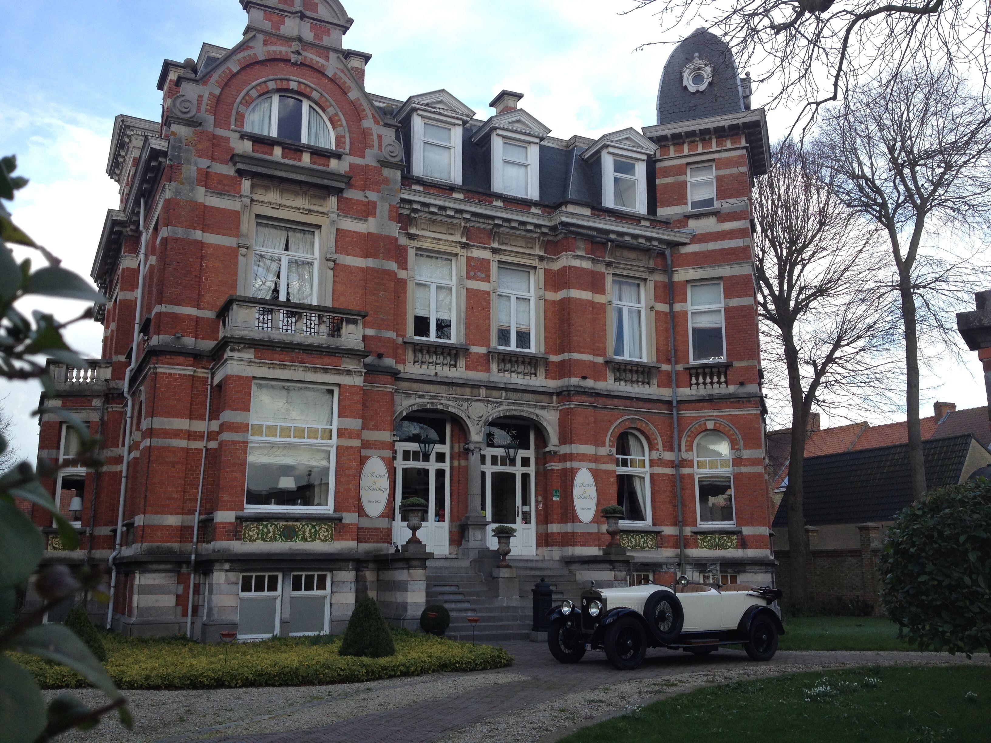 Een groot, historisch gebouw met een symmetrische gevel, veel ramen en een opvallende ingang.