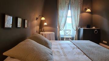 A bedroom with two beds, a desk, a chair, and a window with curtains.