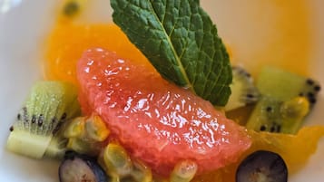 A plate with various fruits and a mint leaf.