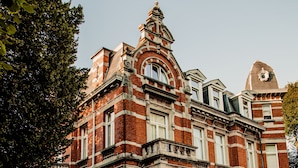 Un edificio grande e histórico con una fachada simétrica, numerosas ventanas y una entrada central destacada.