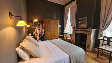 A bedroom with a large bed, wooden wardrobe, and a fireplace.