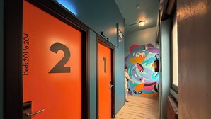A hallway with doors labeled "Beds 201 to 204" and a colorful mural on the wall. - QUO Milano - Hostel (Milan)