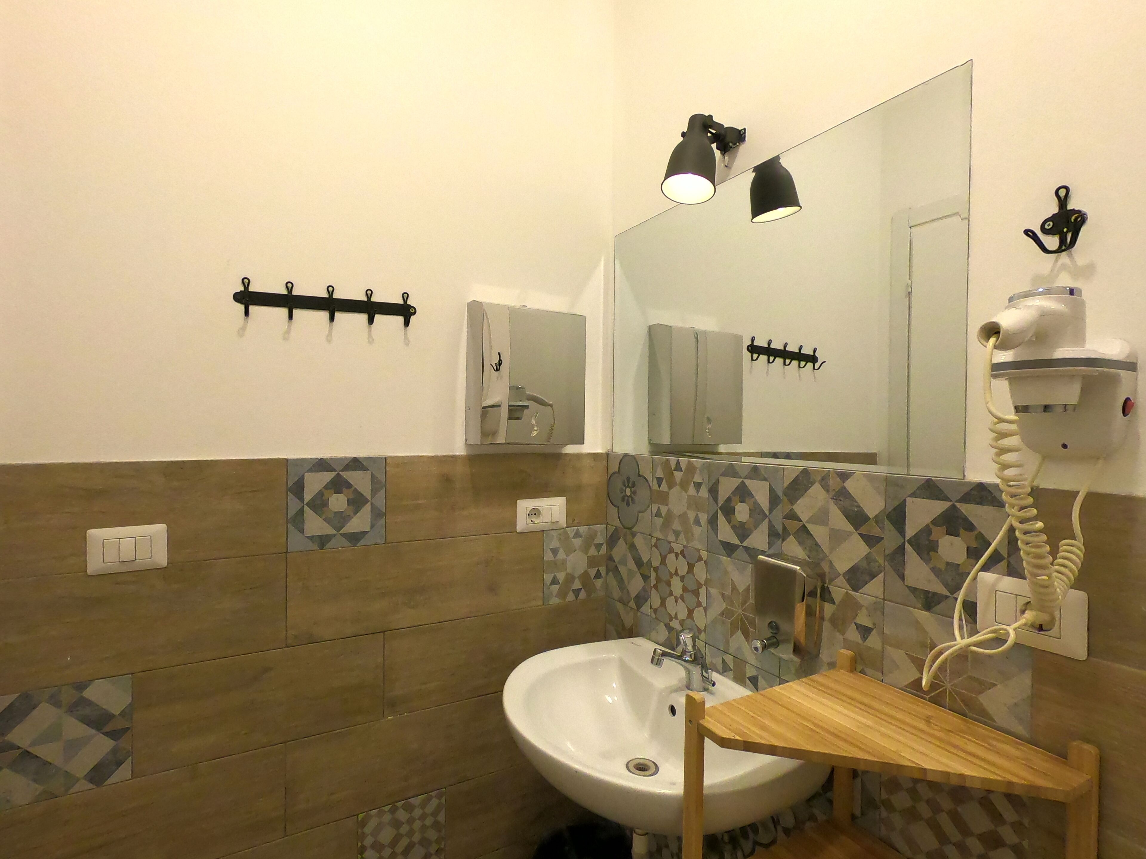 A bathroom with a white sink, a mirror, a wooden vanity, and a towel rack.