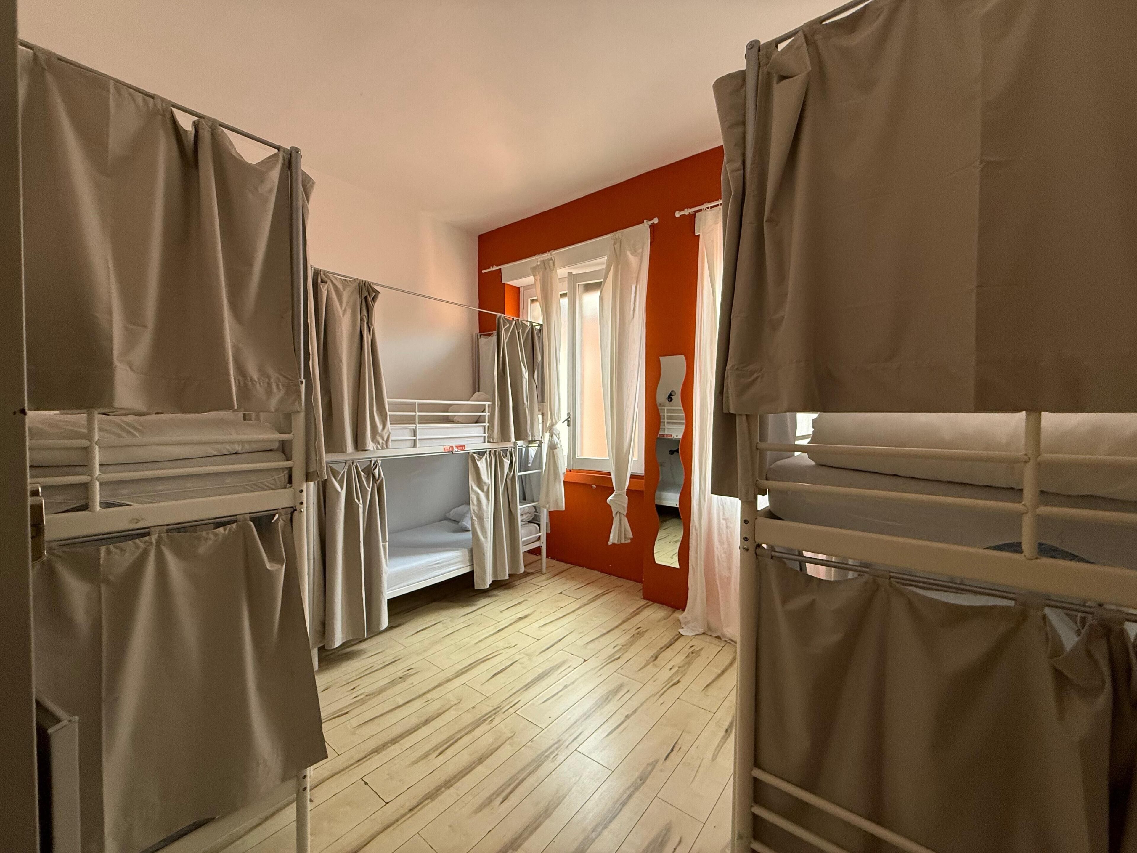 Un dormitorio con literas, suelo de madera y una ventana con cortinas.