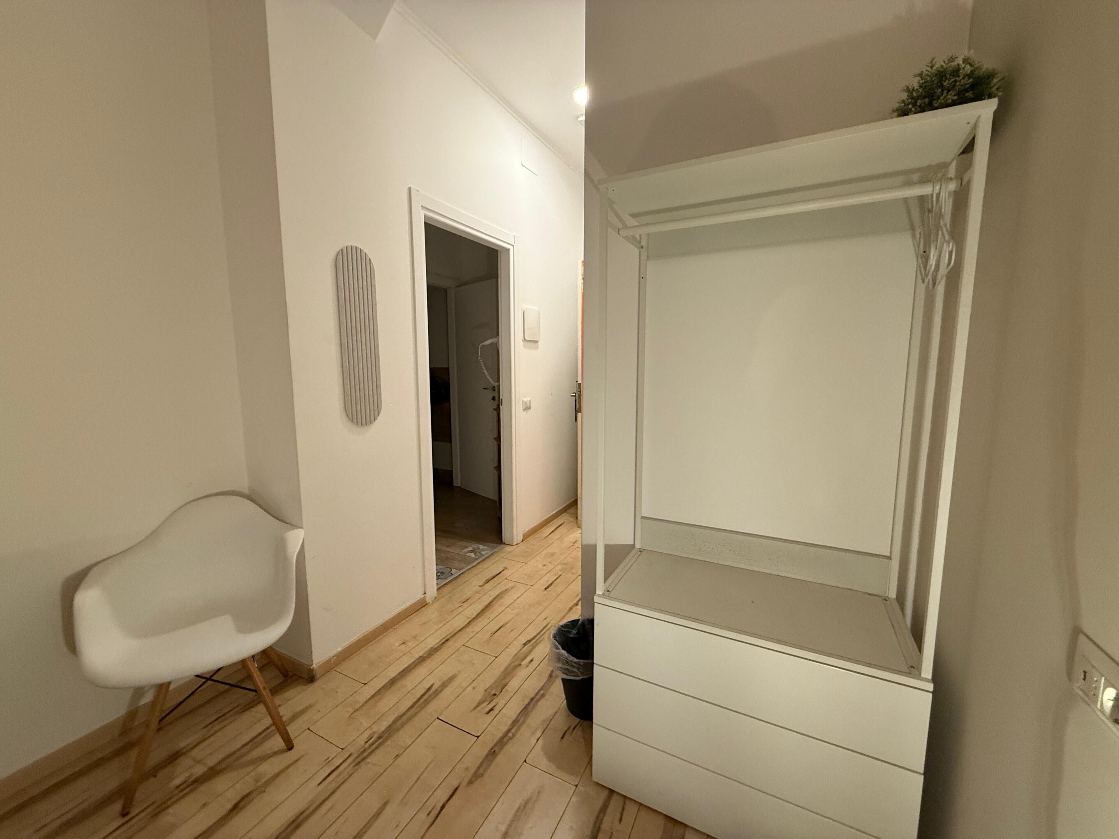 A room with a white wardrobe, a white chair, and a wooden floor.