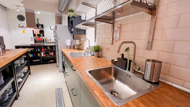 A modern kitchen with stainless steel appliances, a wooden countertop, and a built-in sink. - QUO Milano - Hostel (Milan)