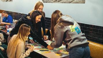 A group of people seated at a table in a restaurant, engaged in a collaborative activity with papers and markers.