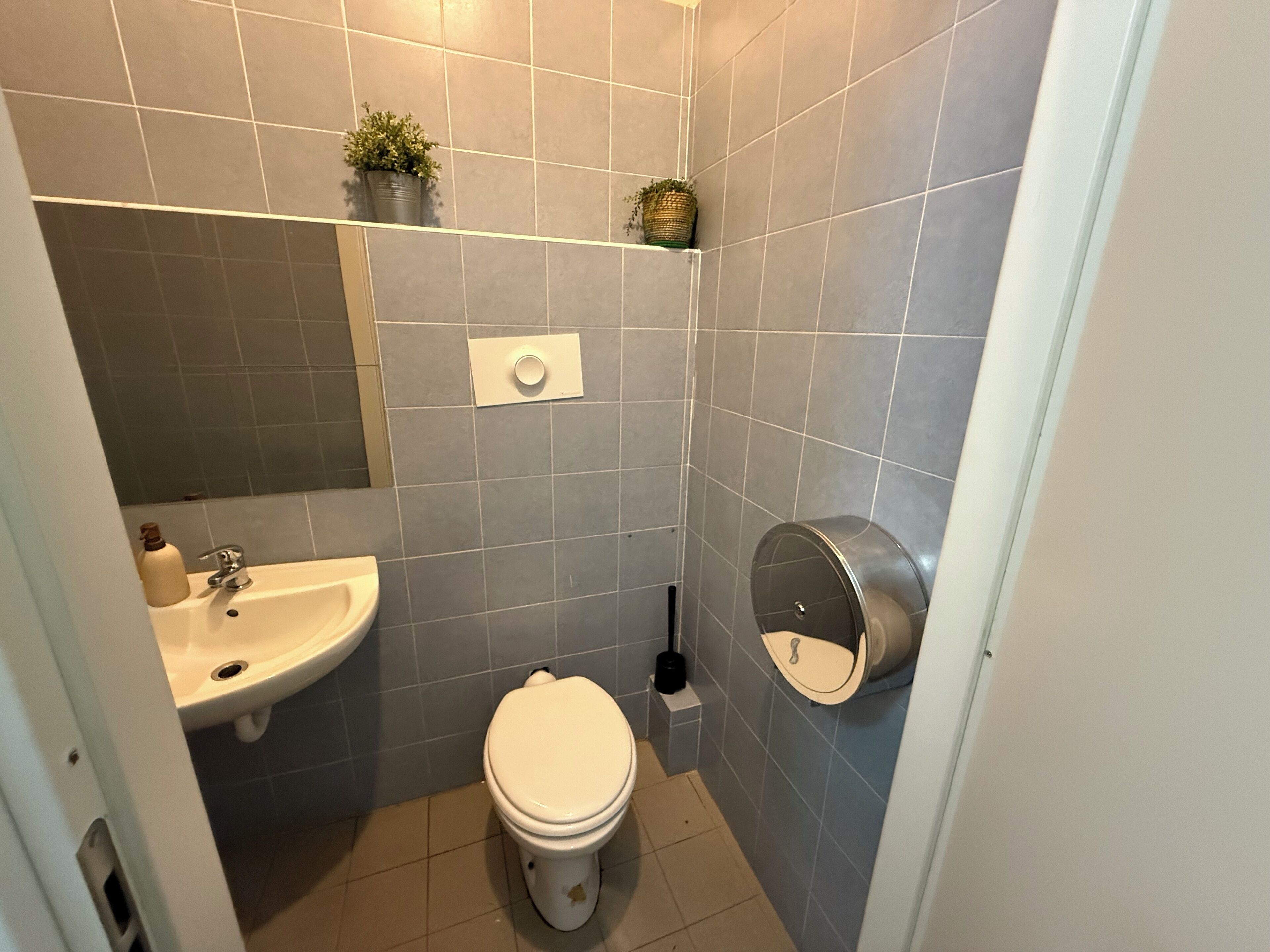 A small bathroom with a toilet, sink, and a hand dryer.