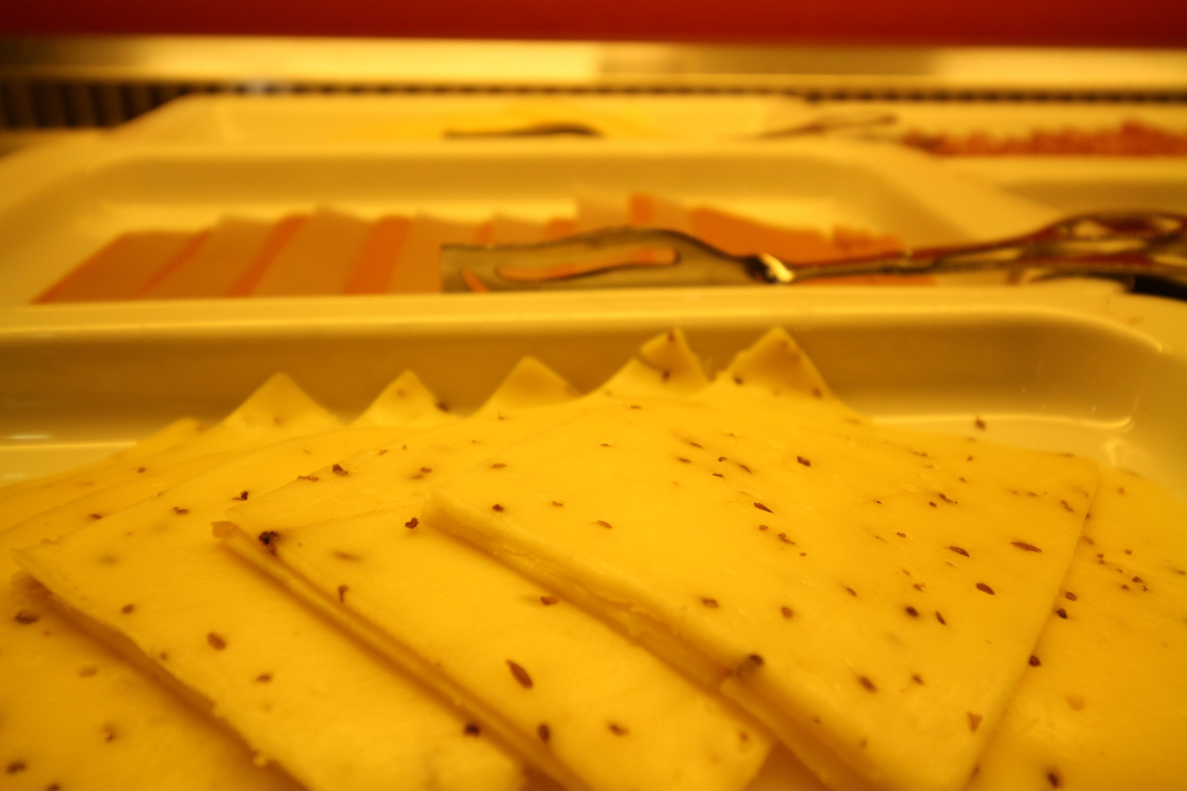 A tray of sliced cheese with a serrated edge.