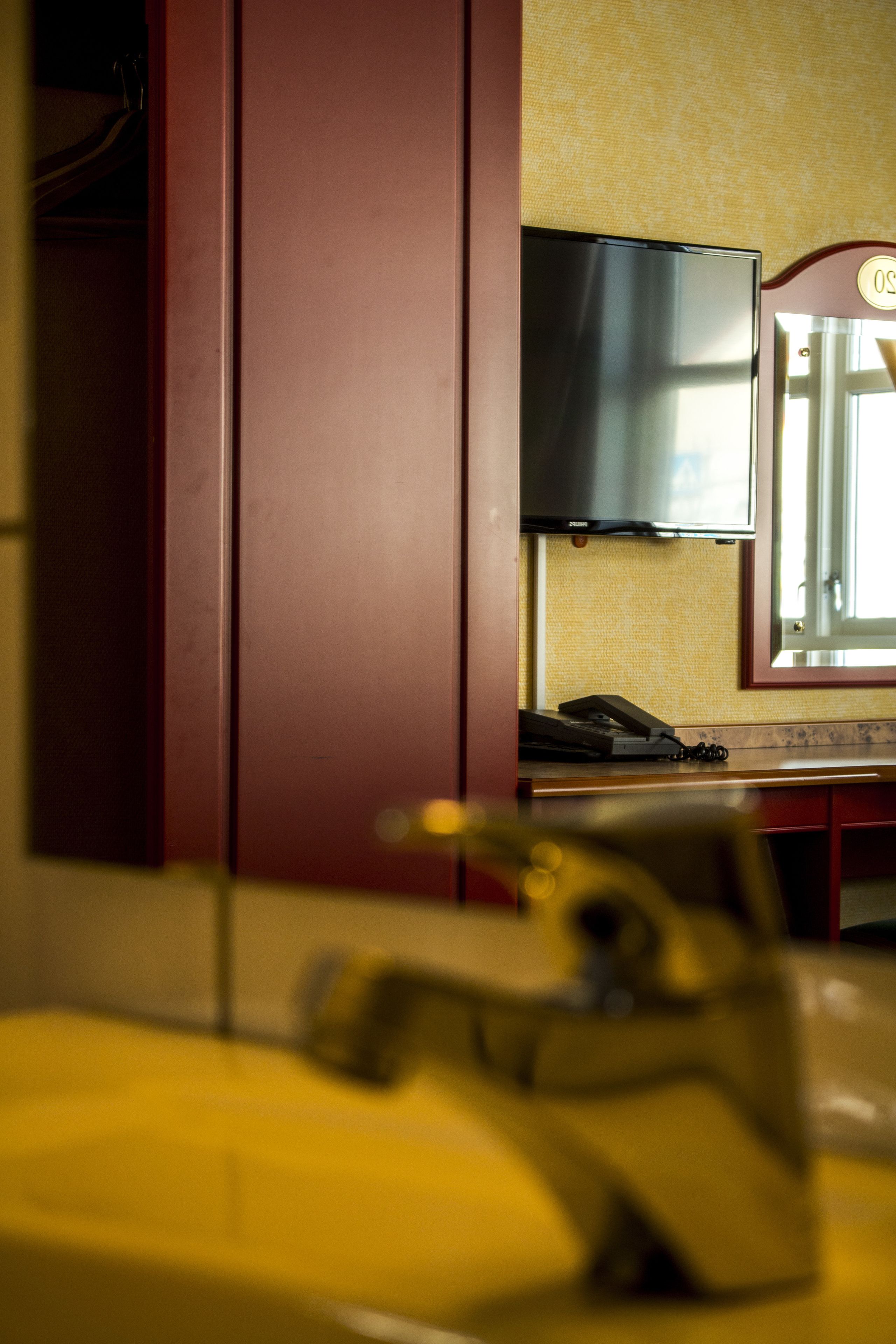 A bathroom with a sink, mirror, and a television mounted on the wall.