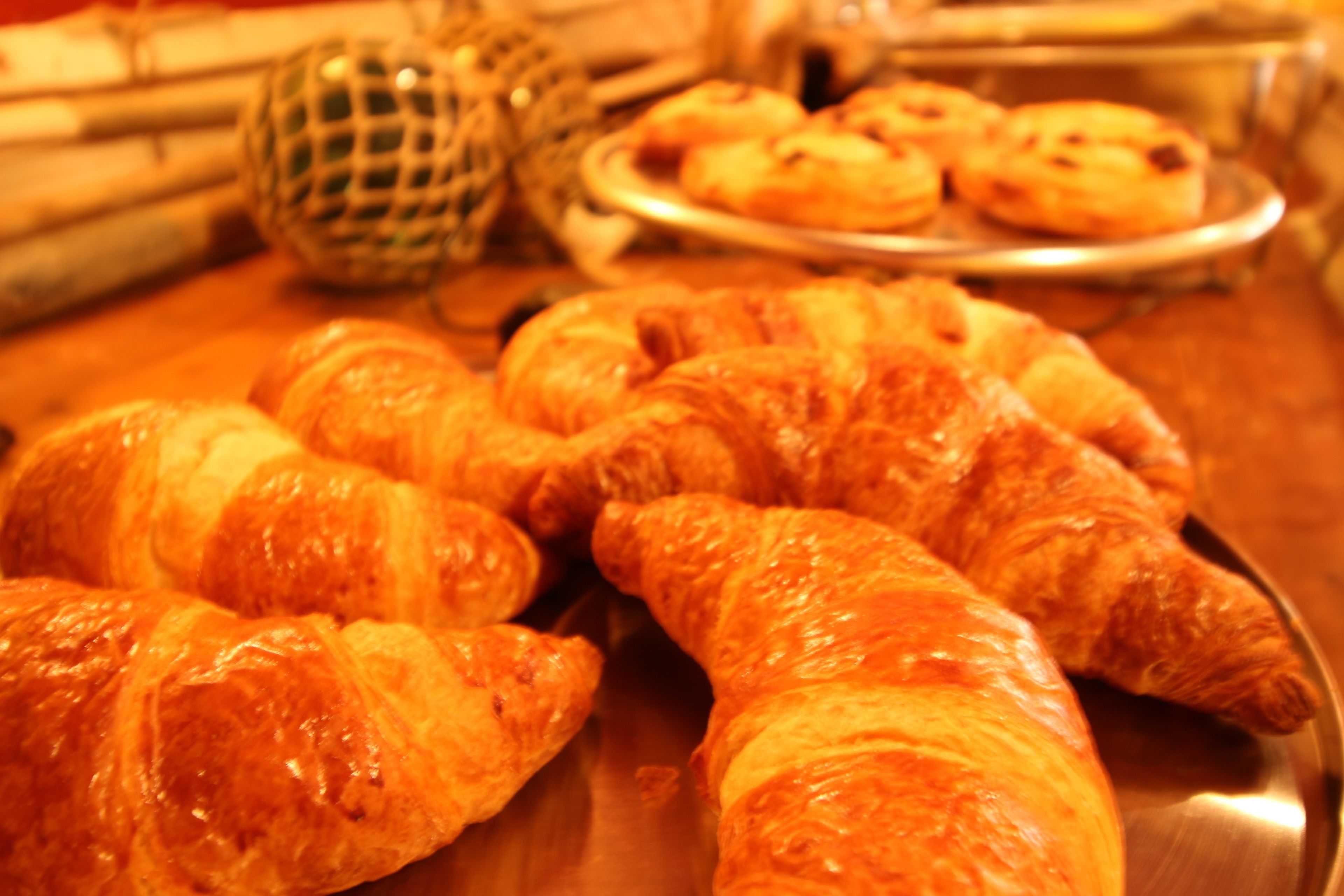 Diversos pastéis, incluindo croissants, em uma bandeja de metal.