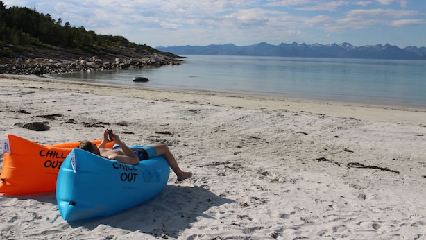 A beach with two inflatable tubes labeled "CHILL OUT" and a person lying on one of them. - Tysfjord Turistsenter (Hamaroy)