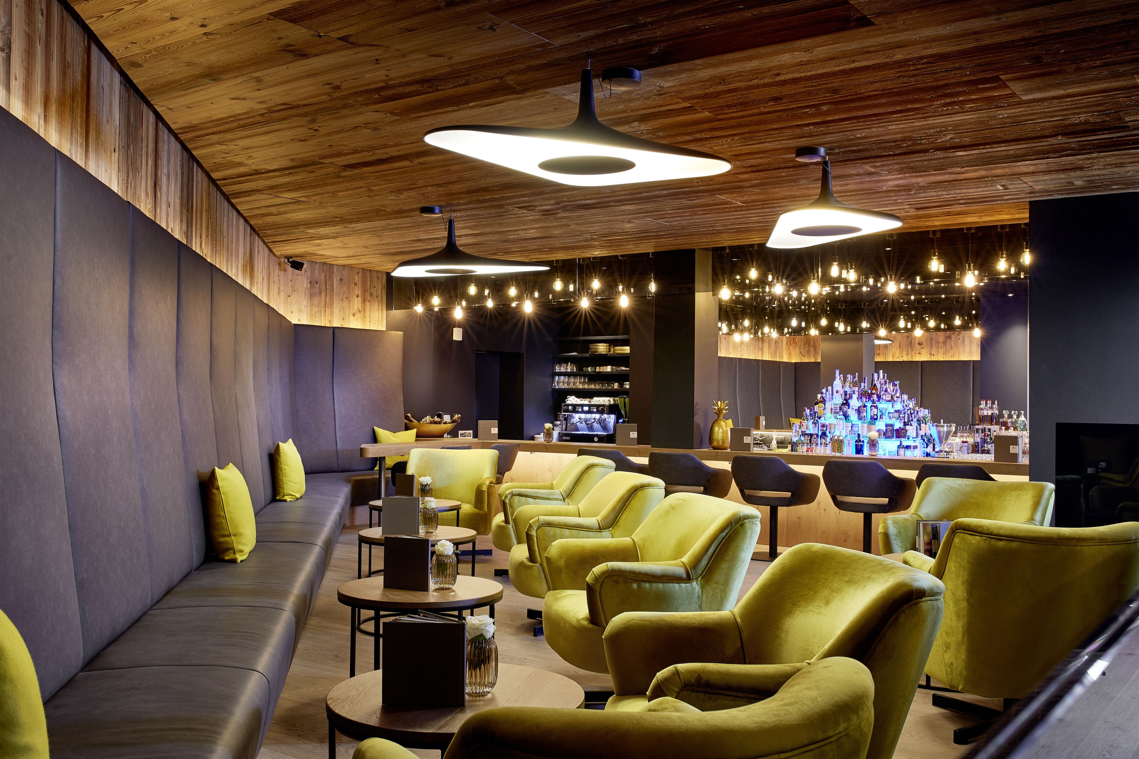Un espace de détente moderne comprenant un bar, des canapés et des tables.
